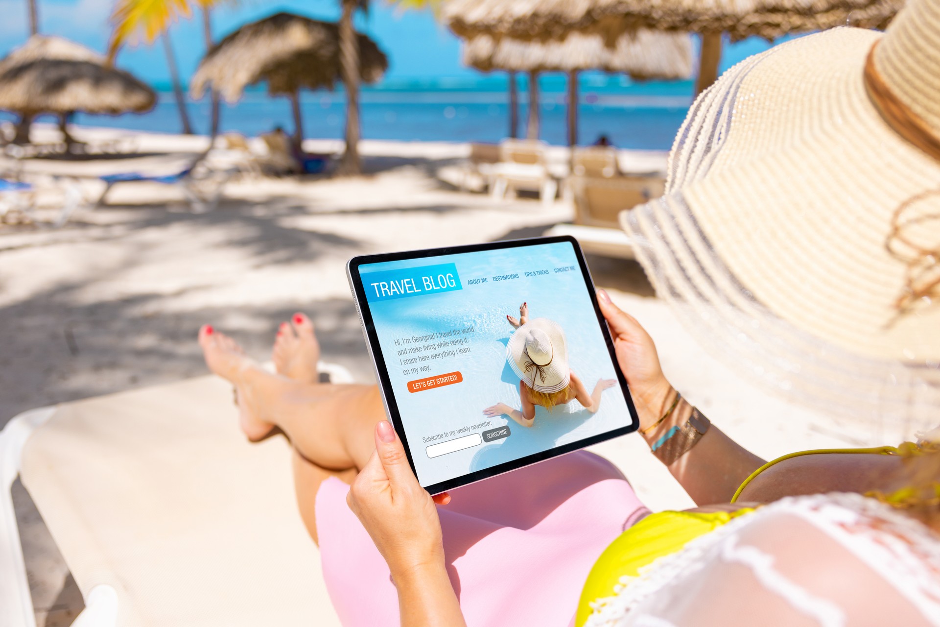 Woman relaxing on beach and reading travel blog on tablet computer